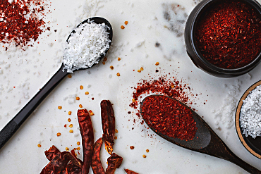 Spoons and bowls with salt and ground and whole red chili peppers